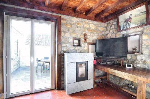 un salon avec une télévision et une cheminée dans l'établissement La Chaumière - Maison à moins d’un km de la plage, à Saint-Jean-de-la-Rivière