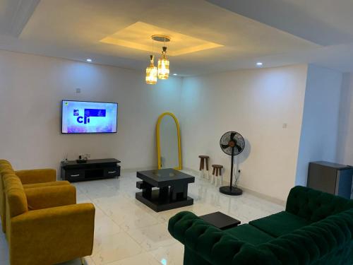 a living room with a couch and a tv on a wall at Charming & Cozy 1-BDR Apt - Mini Flat - 247 Power, Kitchen, Wi-Fi, DSTV, Netflix, 5 mins from the Airports in Ikeja