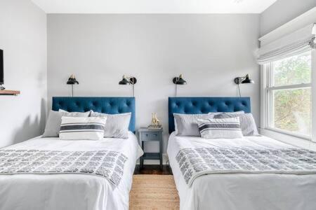 two beds in a white bedroom with blue headboards at The Porter - Chic East Nash Comfort, Dog Welcome in Nashville