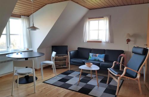 ein Wohnzimmer mit einem Sofa, einem Tisch und Stühlen in der Unterkunft Pyttegården Apartments in Gudhjem