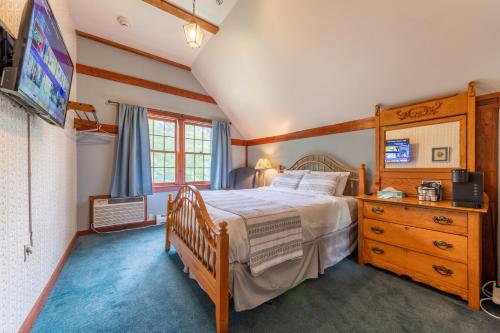 1 dormitorio con 1 cama, vestidor y TV en Cranmore Mountain Lodge Bed & Breakfast en North Conway