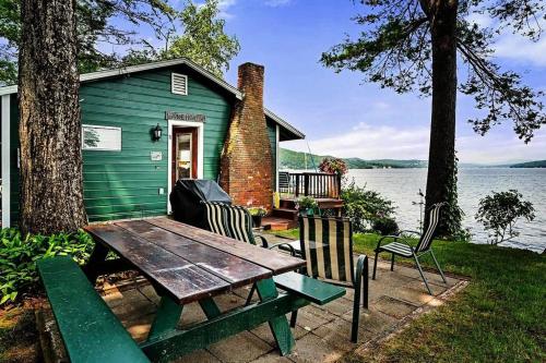 a green house with a picnic table in front of a lake at Winnipesaukee Lakefront w/ Dock in Laconia