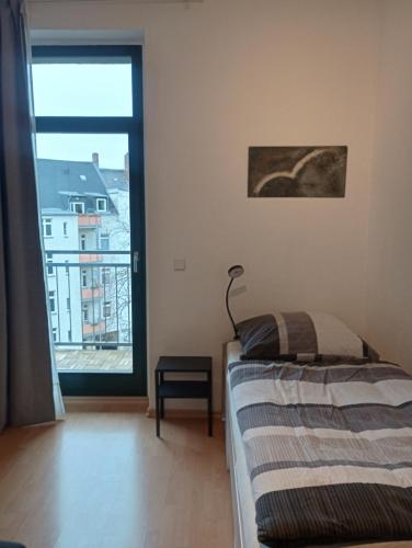 a bedroom with a bed and a large window at Ferienwohnung Stefan Heym am Kaßberg in Chemnitz