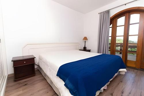 a bedroom with a large bed with a blue blanket at Quatre Saison 308 in Campos do Jordão