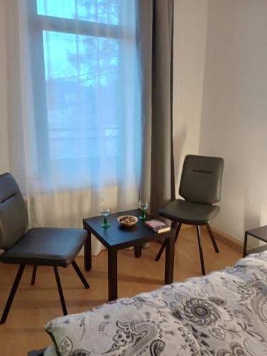 a room with a bed and two chairs and a table at Ferienwohnung Stefan Heym am Kaßberg in Chemnitz