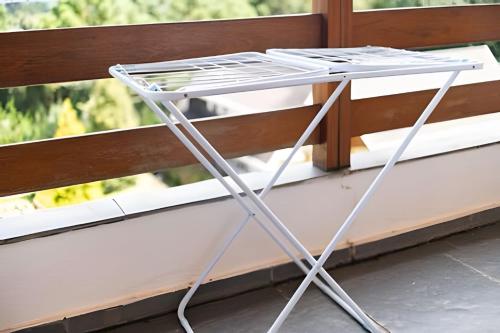 a metal folding table in front of a window at Quatre Saison 308 in Campos do Jordão