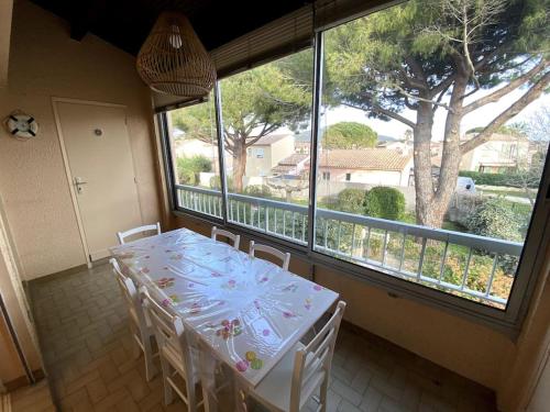 une table et des chaises dans une pièce avec une grande fenêtre dans l'établissement Bel appartement proche des criques - Climatisé, à Six-Fours-les-Plages
