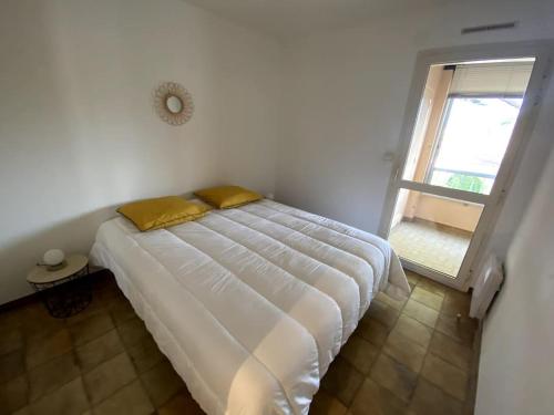a white bed in a room with a window at Bel appartement proche des criques - Climatisé in Six-Fours-les-Plages