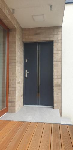 a black door on a brick wall with a wooden floor at Near the airport- Apartments in Kraków