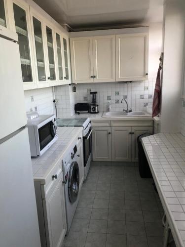 une cuisine avec des armoires blanches et une machine à laver dans l'établissement Résidence Saint-Remy, à Saint-Denis