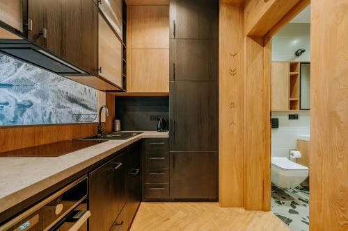 Una cocina con armarios de madera, un fregadero y un inodoro. en Krupówki 25A Górski Loft by Homeprime, en Zakopane