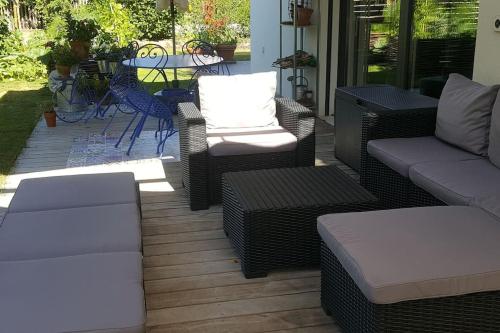 eine Terrasse mit Korbmöbeln sowie einem Tisch und Stühlen in der Unterkunft Appartement dans un jardin in Genf