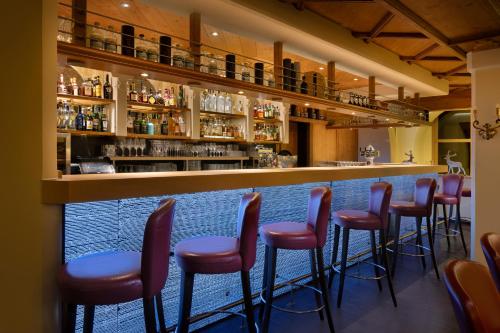 a bar with a row of red stools at Arabella Alpenhotel am Spitzingsee, a Tribute Portfolio Hotel in Spitzingsee