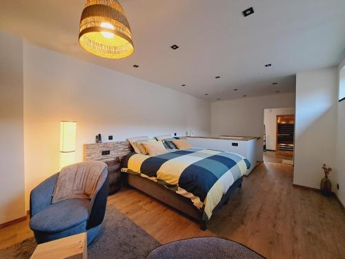 1 dormitorio grande con 1 cama y 1 silla en AMIKALEMENT VÔTRE - Gîte 2 personnes en La Roche-en-Ardenne