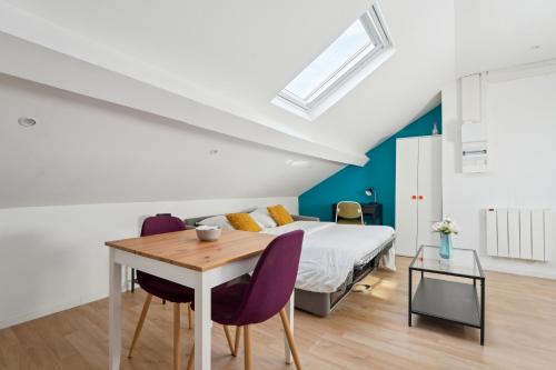 een slaapkamer met een bed en een tafel met paarse stoelen bij Appartement budget avec parking au centre-ville in Charleville-Mézières