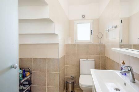 a bathroom with a toilet and a sink and a window at Joya Cyprus Mermaid Penthouse Apartment in Saint Amvrosios