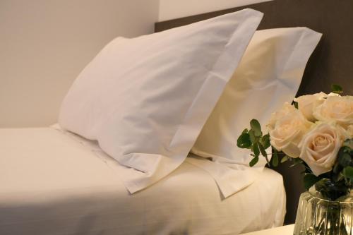 a bed with white pillows and a vase of flowers at Emerald Green Residence in Caldiero