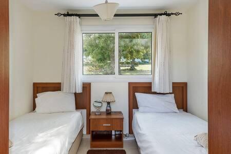a bedroom with two beds and a window at Joya Cyprus Maroon Garden Apartment in Saint Amvrosios