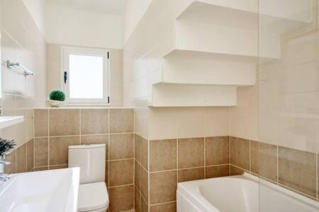 a bathroom with a toilet and a tub and a sink at Joya Cyprus Mandalay Penthouse Apartment in Saint Amvrosios