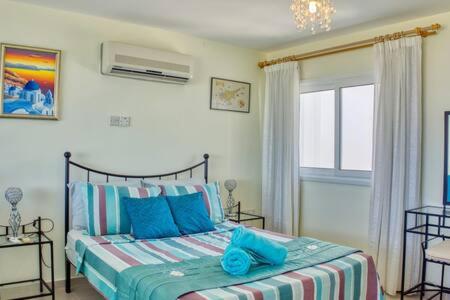 a bedroom with a bed with blue pillows and a window at Joya Cyprus Sapphire Garden Apartment in Saint Amvrosios
