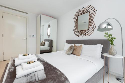 a bedroom with a large white bed with a mirror at Stylish Central 2BR Flat, Belgravia, Chelsea in London