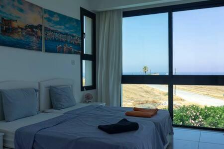 a bedroom with a bed and a large window at Joya Cypern Seaside Luxurious Villa and Private Pool in Akanthou