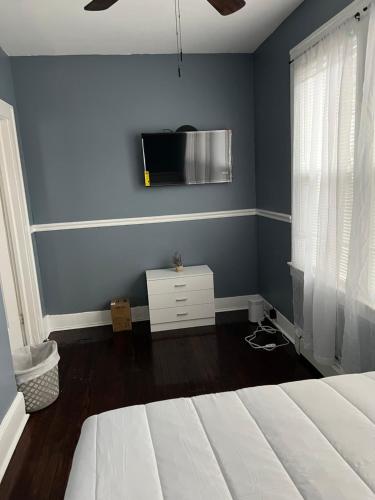 a bedroom with a bed and a tv on a wall at Cozy Room in Private Home in Irvington