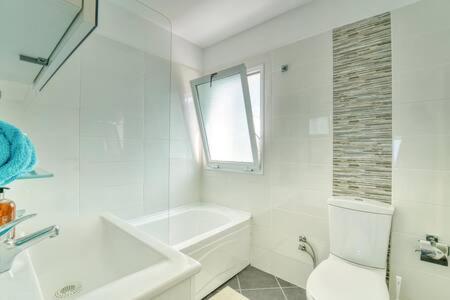 een witte badkamer met een bad, een toilet en een wastafel bij Joya Cyprus Sea Sunset View Garden Apartment in Arsos