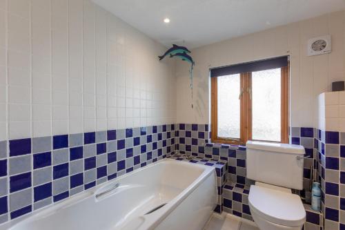 La salle de bains est pourvue d'une baignoire, de toilettes et de carrelage bleu. dans l'établissement Sunset View, à Bude