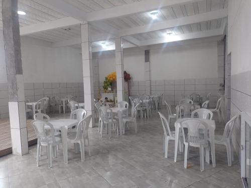 uma sala de jantar com mesas brancas e cadeiras brancas em Cobertura na praia da Ribeira, temporada de carnaval de 09 a 14/02 em Angra dos Reis