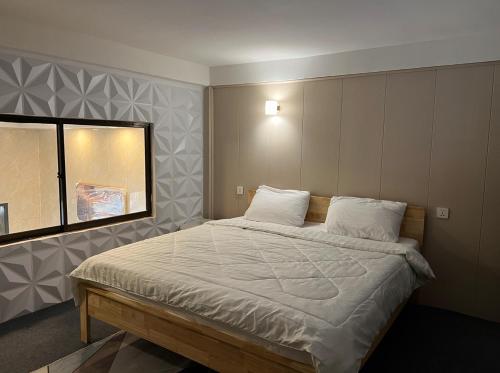 um quarto com uma cama com lençóis brancos e uma janela em White House Guesthouse (Feel like your house) em Phnom Penh