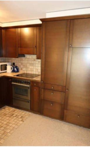 una cucina con armadi in legno e frigorifero in acciaio inossidabile di Gemütliche 2.5Zi Wohnung mit Traum-Aussicht a Falera
