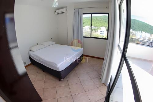 Habitación pequeña con cama y ventana en Cobertura duplex com linda vista para o mar de Bombas, en Bombinhas