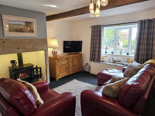 a living room with two leather couches and a fireplace at Hop Cottage in Mirfield