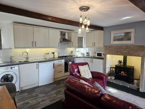 a kitchen and living room with a couch and a fireplace at Hop Cottage in Mirfield