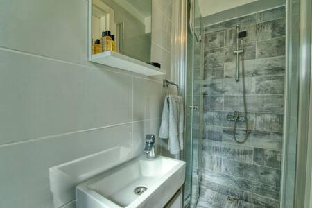 uma casa de banho branca com um lavatório e um chuveiro em Joya Cyprus Sugarberry Garden Apartment em Saint Amvrosios