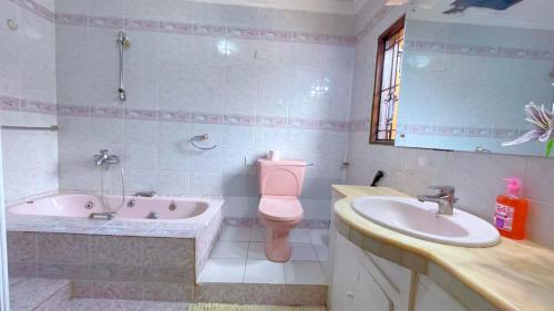 a bathroom with a tub and a toilet and a sink at Villa Ella in Mombasa