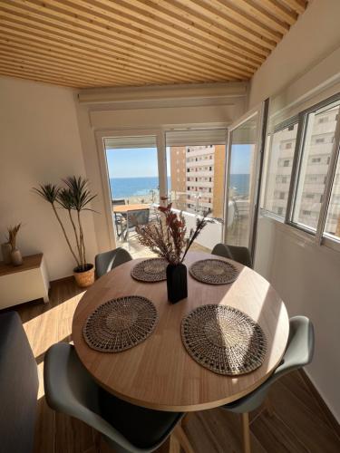 Apartamento Ronda III في فوينخيرولا: غرفة طعام مع طاولة وإطلالة على المحيط