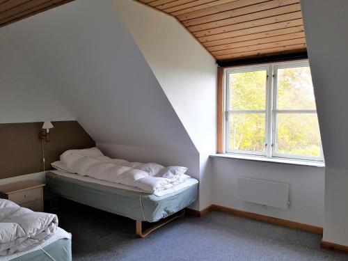 a attic room with two beds and a window at Pyttegården Apartments in Gudhjem