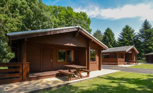 a wooden cabin with a picnic table in the yard at Pinecroft Lodges in Ingleton 