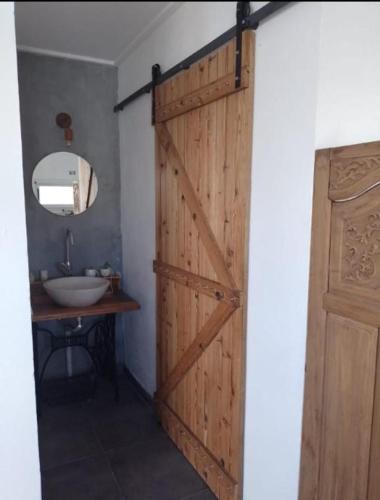uma porta de madeira numa casa de banho com um lavatório em CALIDO QUINCHO em Tandil