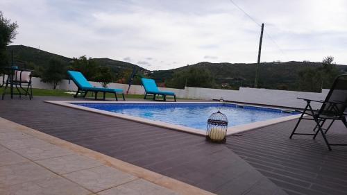 a swimming pool with chairs and a lamp next to it at Casa Das Oliveiras in Alvados