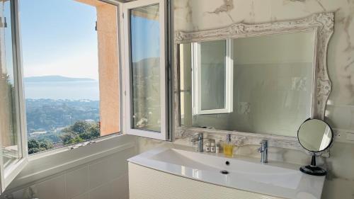 um lavatório de casa de banho com um espelho e uma janela em Villa Cacharelle Vue Mer em Cavalaire-sur-Mer