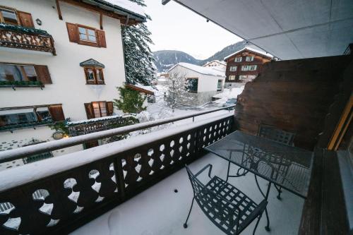 a balcony with a table and chairs in the snow at Alpina Apartments in Klosters