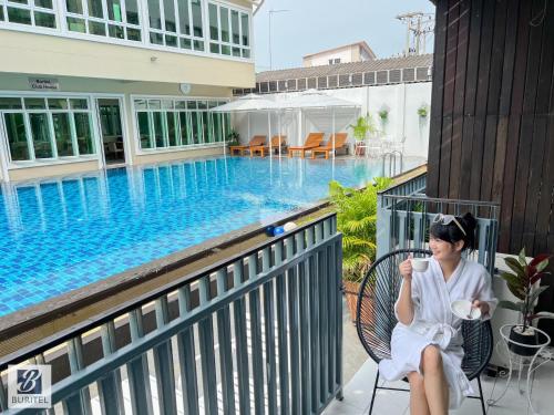a woman sitting in a chair next to a swimming pool at Buritel Hotel in Buriram