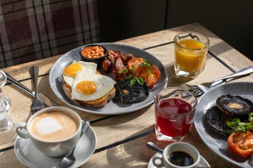 a wooden table with plates of breakfast food and drinks at The White Hart in Castle Combe