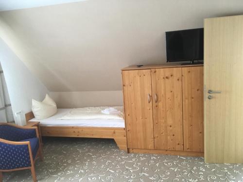 a bedroom with a bed and a cabinet with a television at Hotel Vulkanstüble in Achkarren