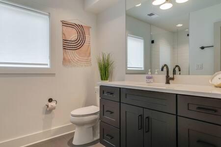 a bathroom with a toilet and a sink and a mirror at Taylor Haus II - Stylish Stay with Rooftop, Close to Fun in Nashville