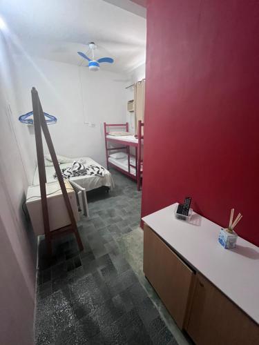 a room with a red wall and a room with a bed at casa de praia in Santos