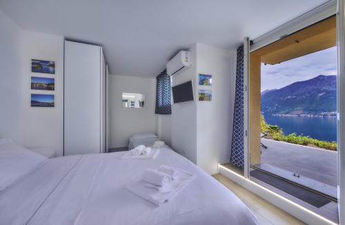 Schlafzimmer mit einem großen Fenster mit Blick auf das Wasser in der Unterkunft Majestic Sunrise Bellagio in Bellagio